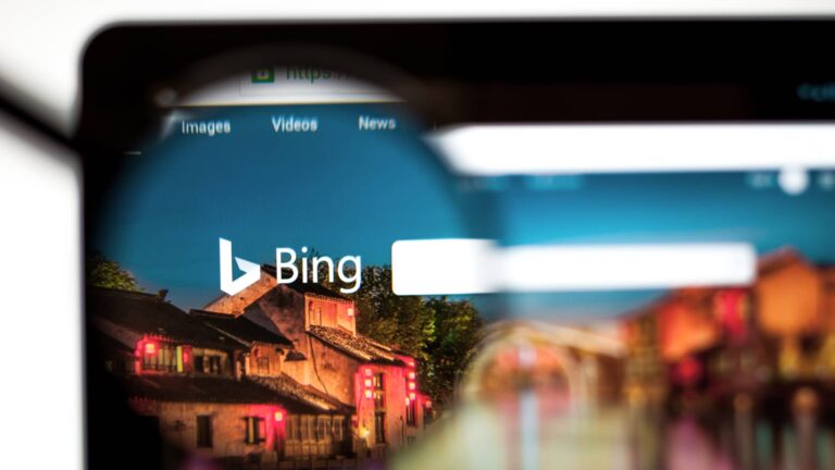 A computer screen shows the Bing search engine homepage, viewed through a magnifying glass.