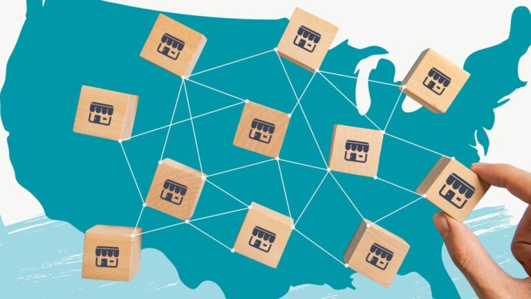 A hand connects wooden blocks with store icons over a map of the United States, illustrating a network of franchises or businesses.