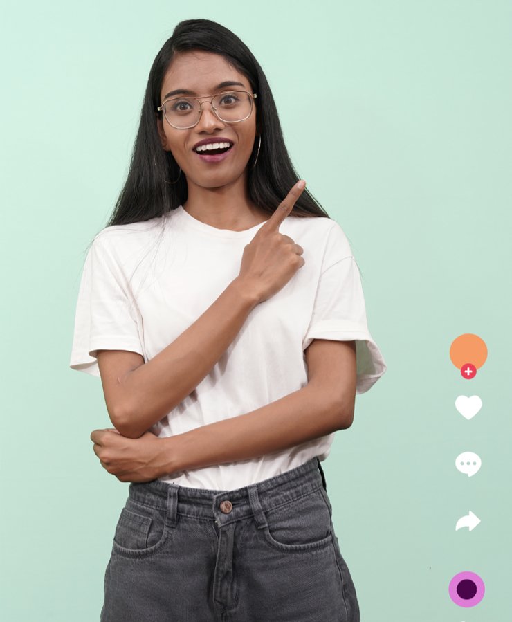 A woman with long hair and glasses, wearing a white t-shirt and jeans, stands against a light green background, smiling and pointing upward. Social media app icons are visible on the right.